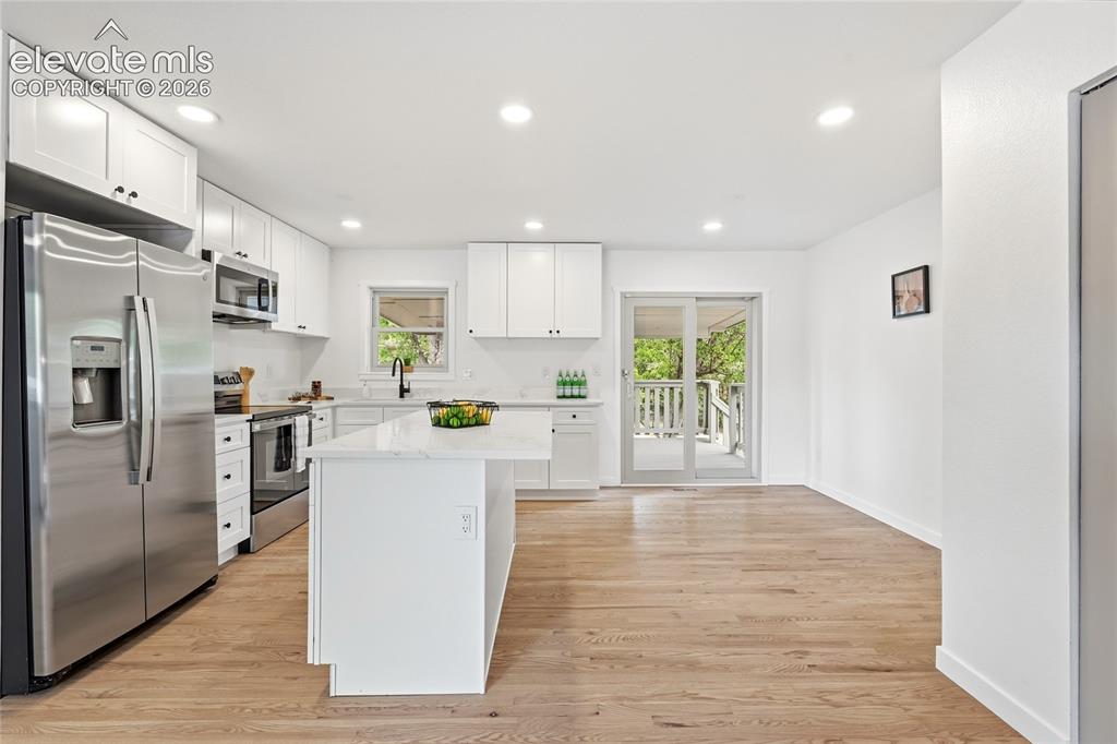 Image 2 of 30: Open-concept kitchen featuring white shaker cabinetry, stainless steel appl