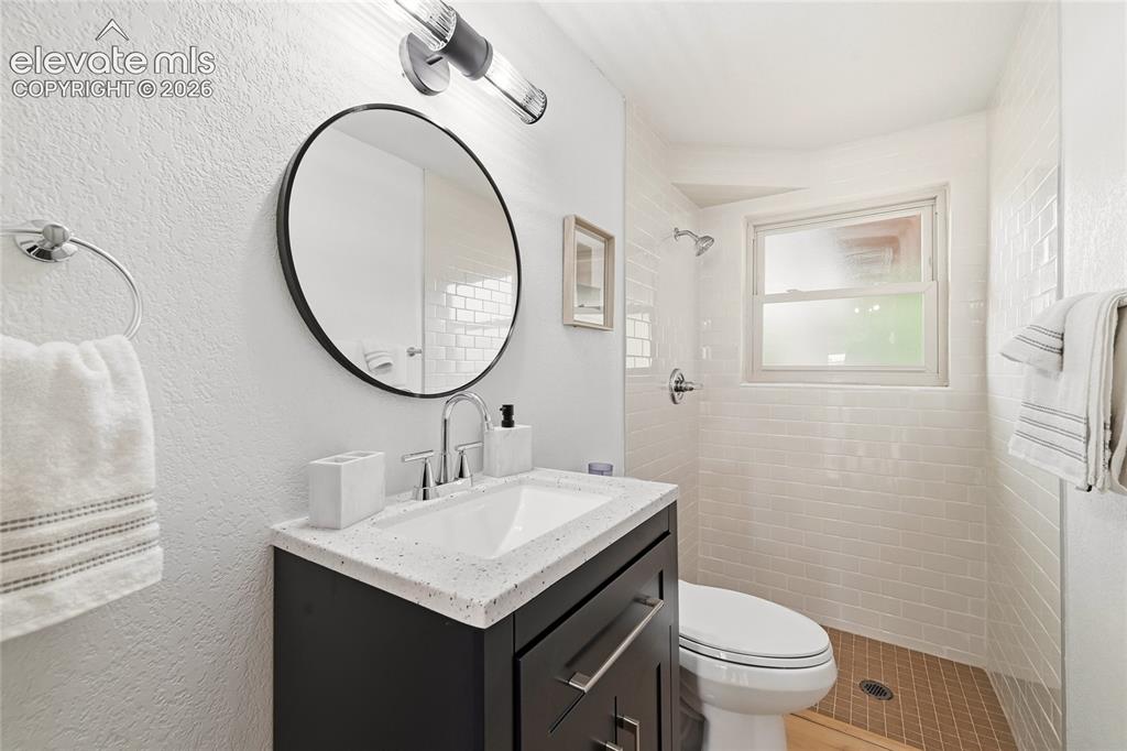 Image 20 of 30: Contemporary bathroom featuring a dark wood-finish vanity with a light spec