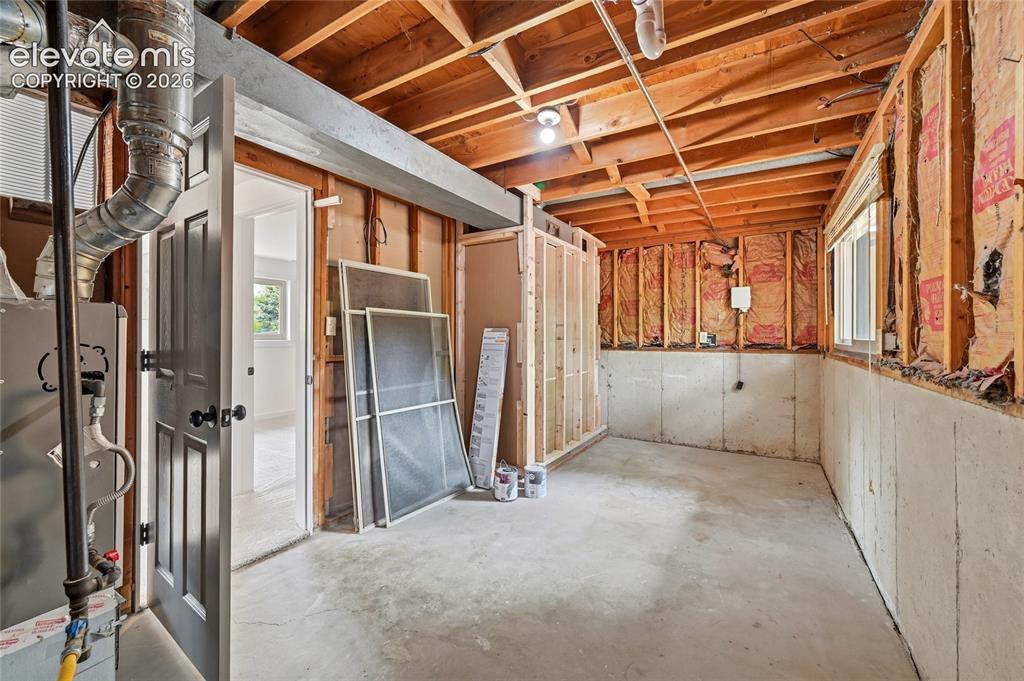 Image 22 of 30: Unfinished lower level featuring exposed wood ceiling joists and wall studs