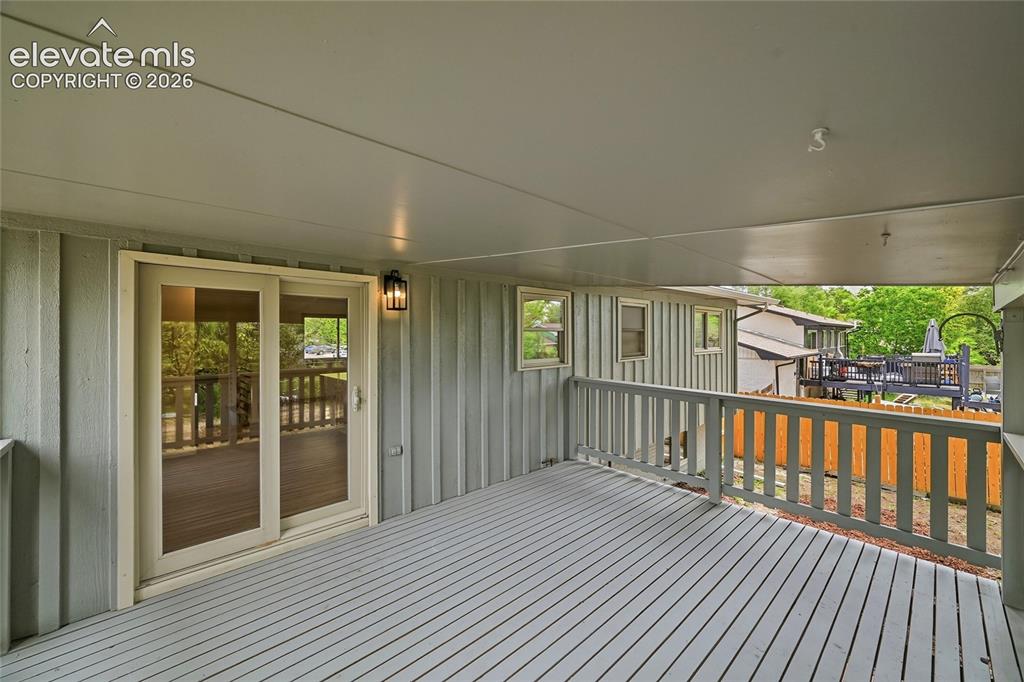 Image 23 of 30: Covered outdoor deck featuring painted wood-finish flooring, a sliding glas