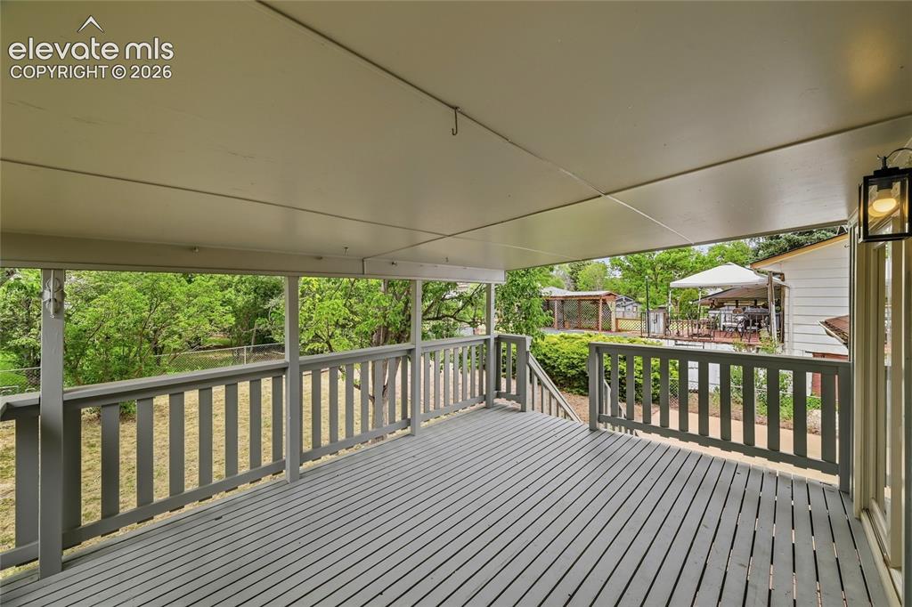 Image 3 of 30: Expansive covered deck featuring painted wood-finish flooring, a full raili