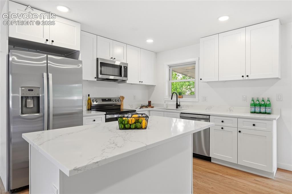 Image 7 of 30: Contemporary kitchen featuring a center island with a stone-finish countert