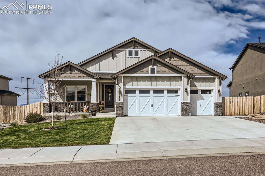 Caption: Craftsman-style home featuring board and batten siding, stone siding, an attached garage, covered po