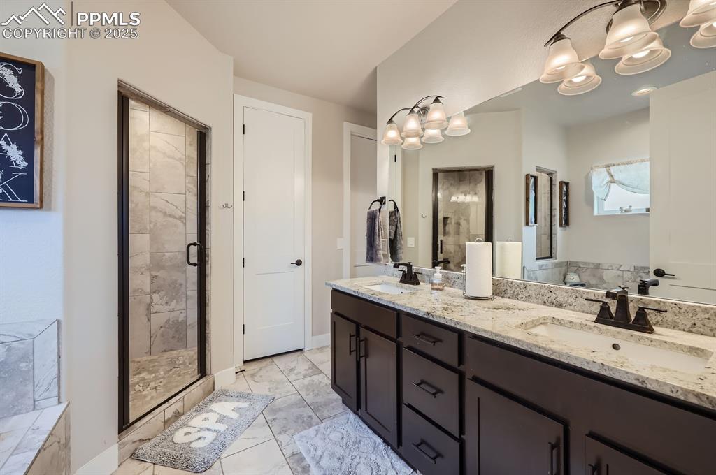 Image 13 of 27: Bathroom with marble finish flooring, a shower stall, a chandelier, double 