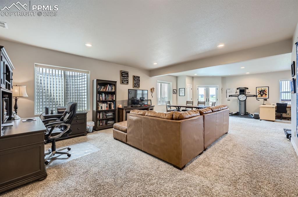 Image 17 of 27: Living area with light colored carpet, an office area, and recessed lightin