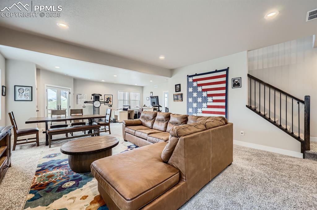 Image 18 of 27: Living area with recessed lighting, carpet, baseboards, and stairs