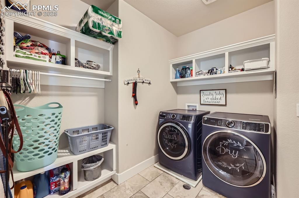 Image 24 of 27: Laundry area featuring washer and clothes dryer, baseboards, and tile patte