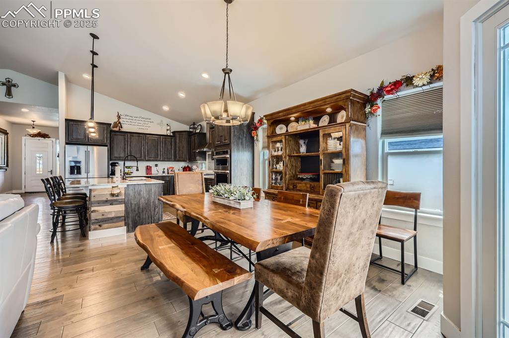 Image 9 of 27: Dining space featuring vaulted ceiling, a chandelier, light wood-type floor