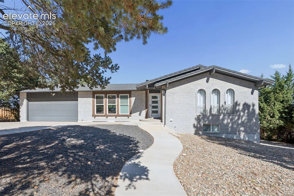 Caption: Single-story residence featuring a painted masonry exterior, attached multi-car garage, arched windo