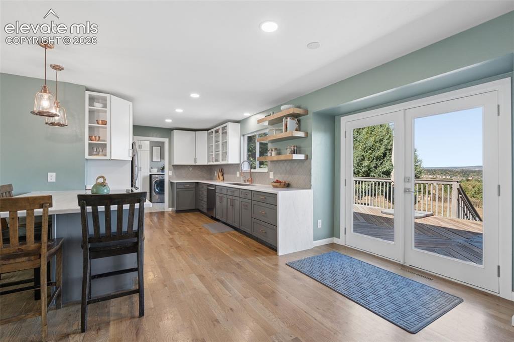 Image 11 of 49: Kitchen featuring shaker-style cabinetry, stone countertops, wood-finish fl