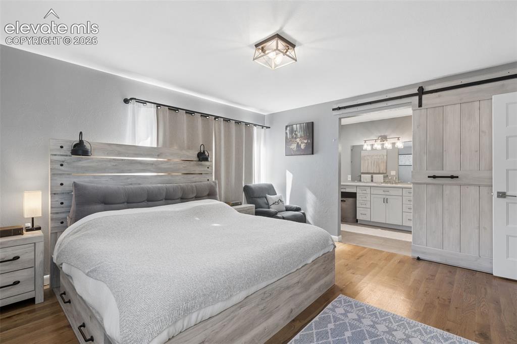 Image 13 of 49: Wood-finish flooring, sliding wood-panel door with matte black hardware, fl