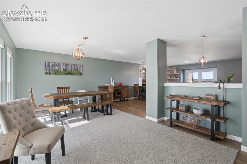Image 22 of 49: Open-concept interior featuring wood-finish flooring, two spherical pendant