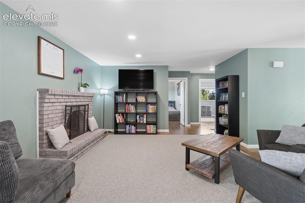 Image 24 of 49: Living area featuring a floor-to-ceiling brick fireplace with a raised hear