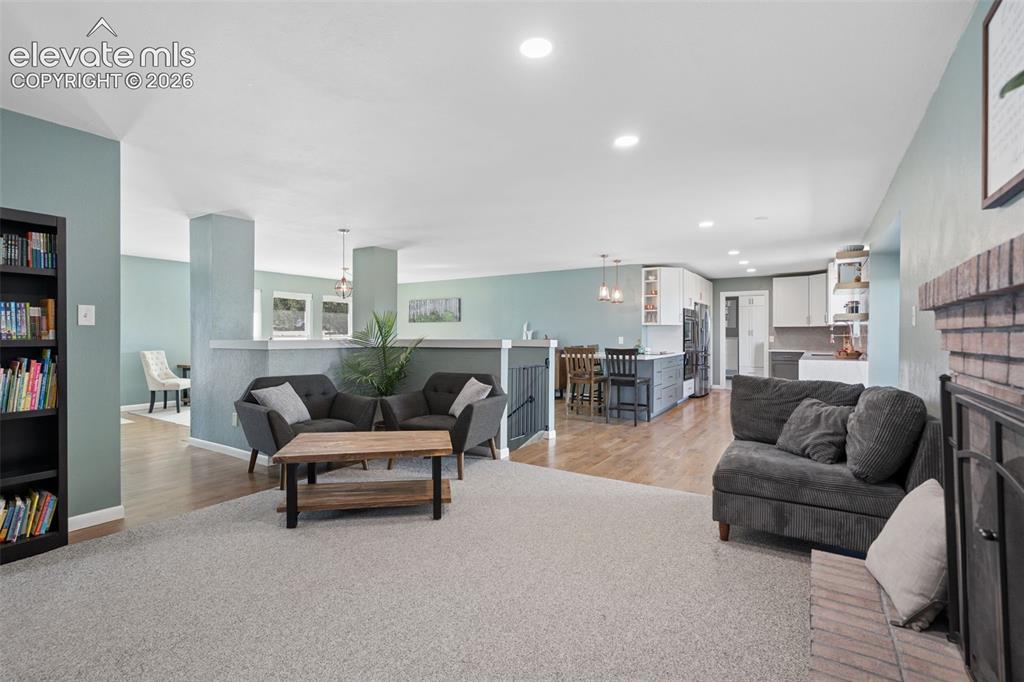Image 25 of 49: Open living area featuring wood-finish flooring, recessed lighting, a brick
