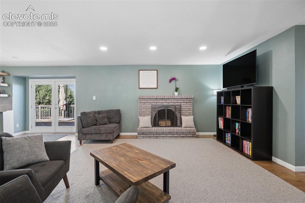 Image 27 of 49: Living area featuring a floor-to-ceiling light brick fireplace, recessed li