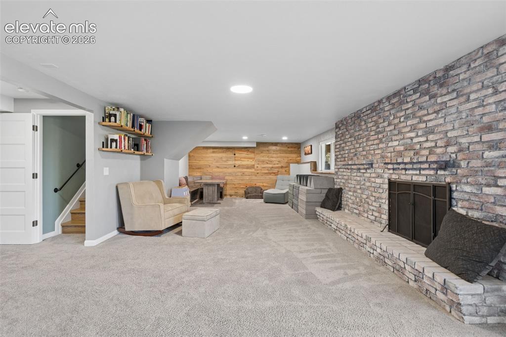 Image 34 of 49: Basement Expansive living area featuring a full-height brick fireplace hear