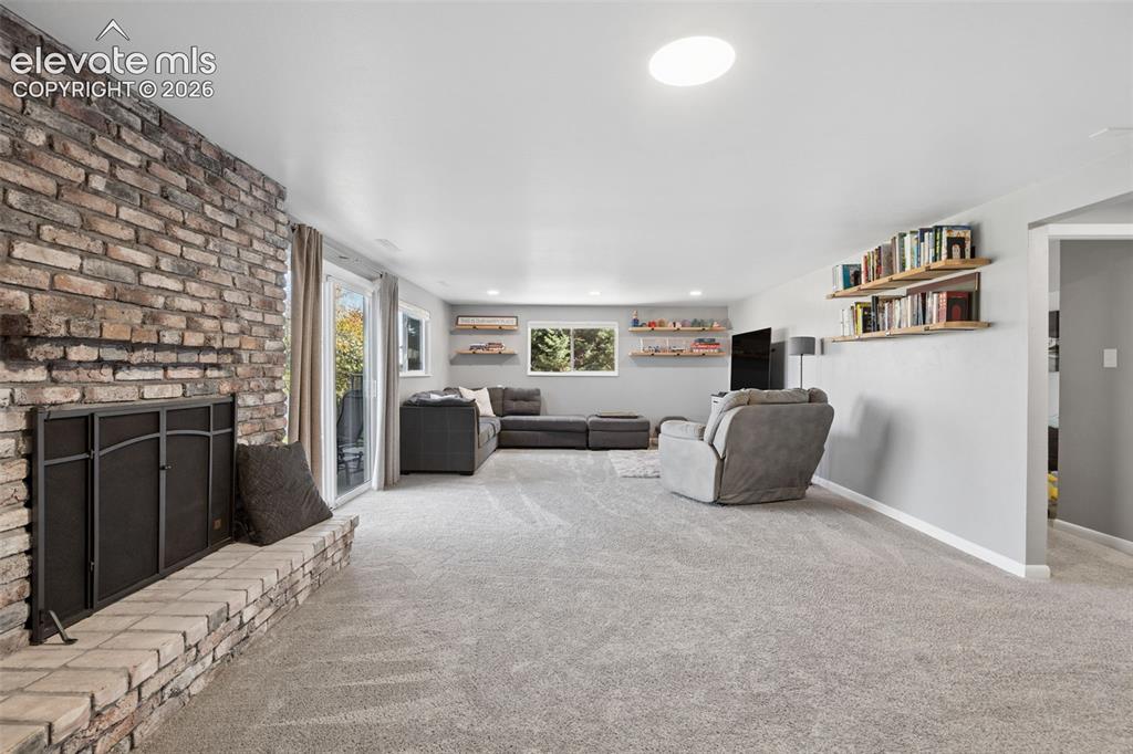 Image 35 of 49: Basement Living area featuring a floor-to-ceiling brick fireplace with a ra