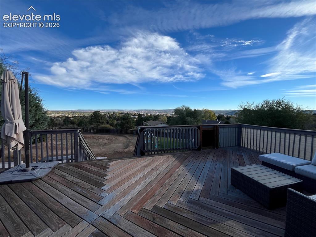 Image 40 of 49: Elevated wood deck featuring a chevron plank pattern, vertical railing, and