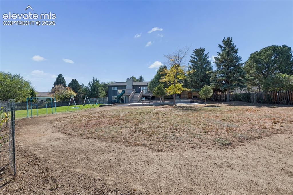 Image 44 of 49: Expansive backyard featuring a multi-level wooden deck, stone-paved patio,