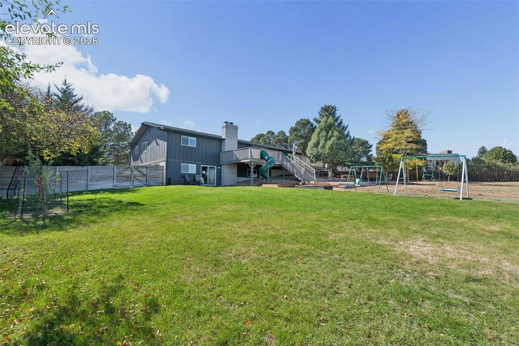 Image 45 of 49: Expansive backyard featuring a multi-level deck, exterior chimney, privacy 