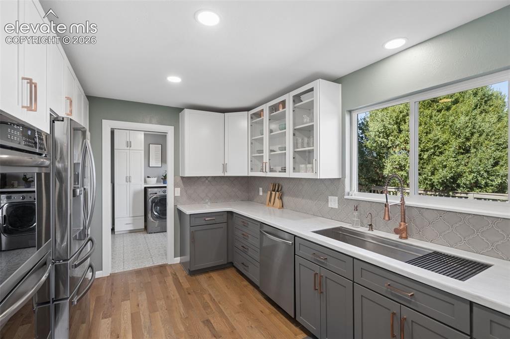 Image 6 of 49: Kitchen featuring white and grey shaker-style cabinetry, white solid-surfac