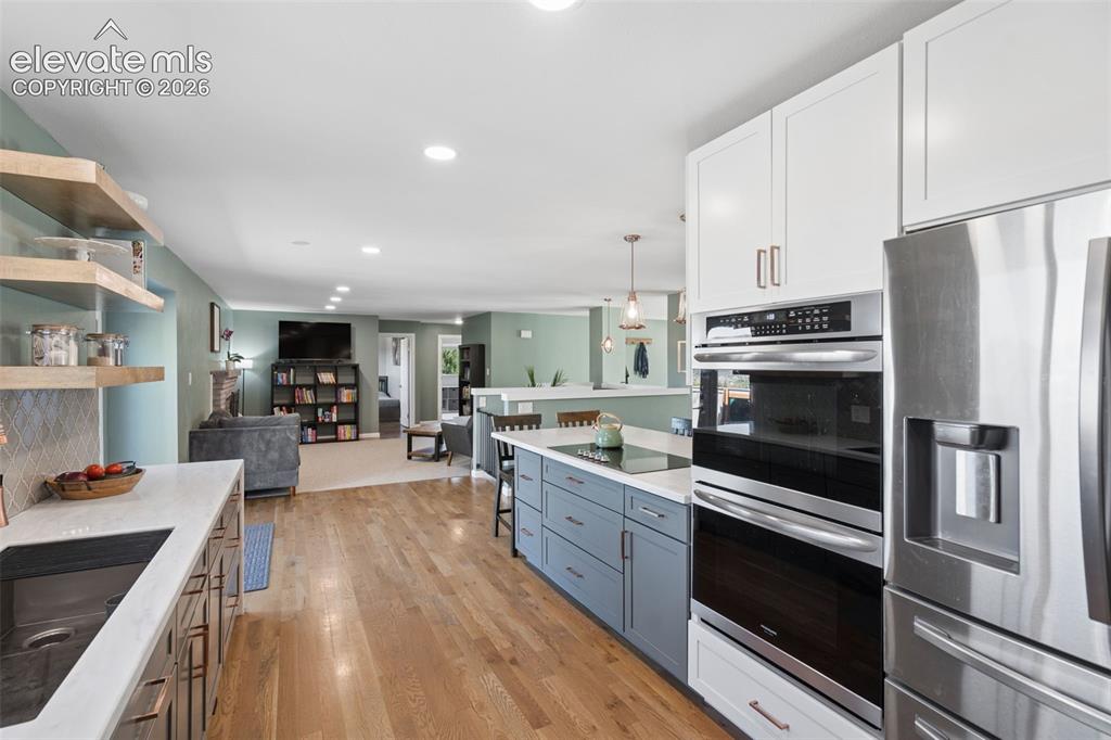 Image 8 of 49: Kitchen featuring white upper cabinetry, blue lower cabinetry, stainless st