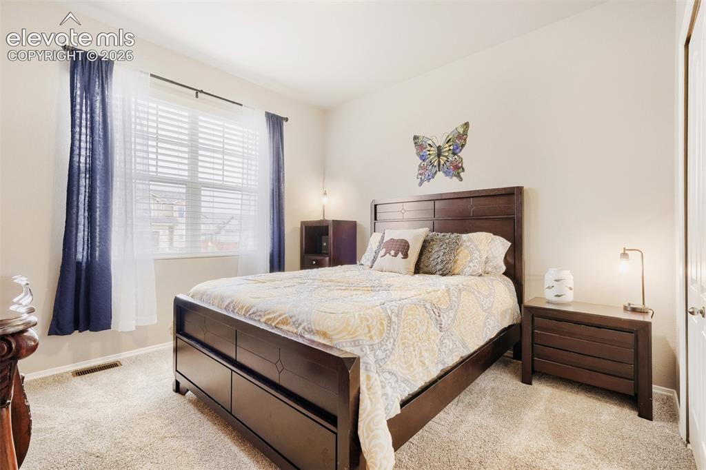 Image 15 of 31: Main level second bedroom featuring a large window with blinds and drapes,