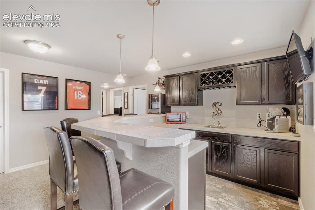 Image 22 of 31: A stylish wet bar entertainment space with a counter bar, pendant lighting,