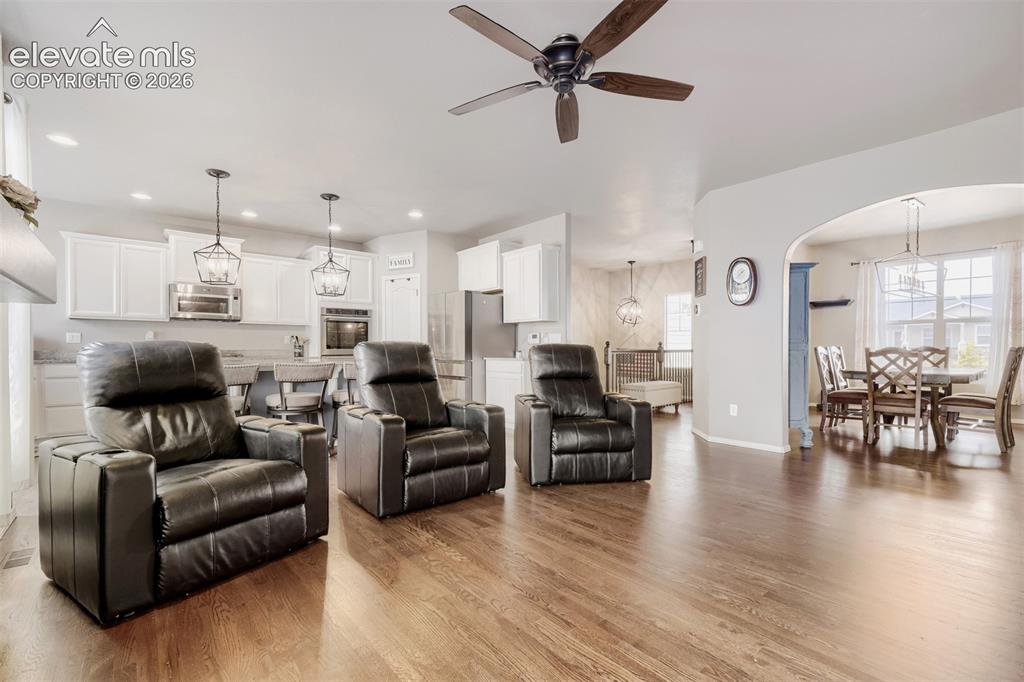 Image 5 of 31: Open concept great room featuring wood flooring, a stacked stone fireplace