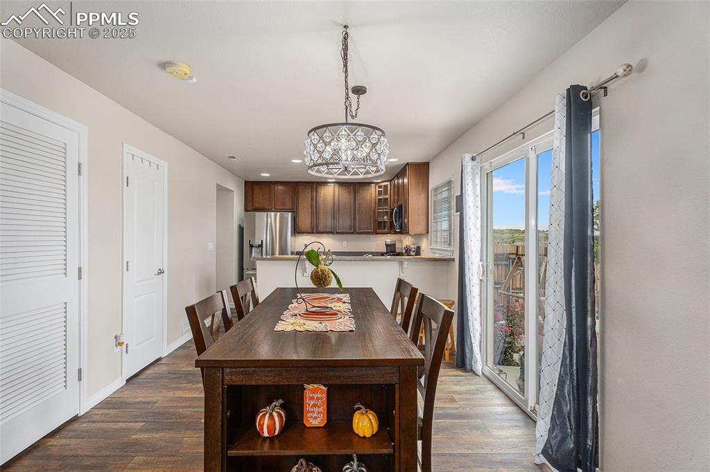 Image 10 of 30: Dining area with dark wood-style floors, a chandelier, and recessed lightin