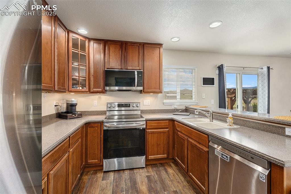 Image 15 of 30: Kitchen with brown cabinetry, appliances with stainless steel finishes, a p