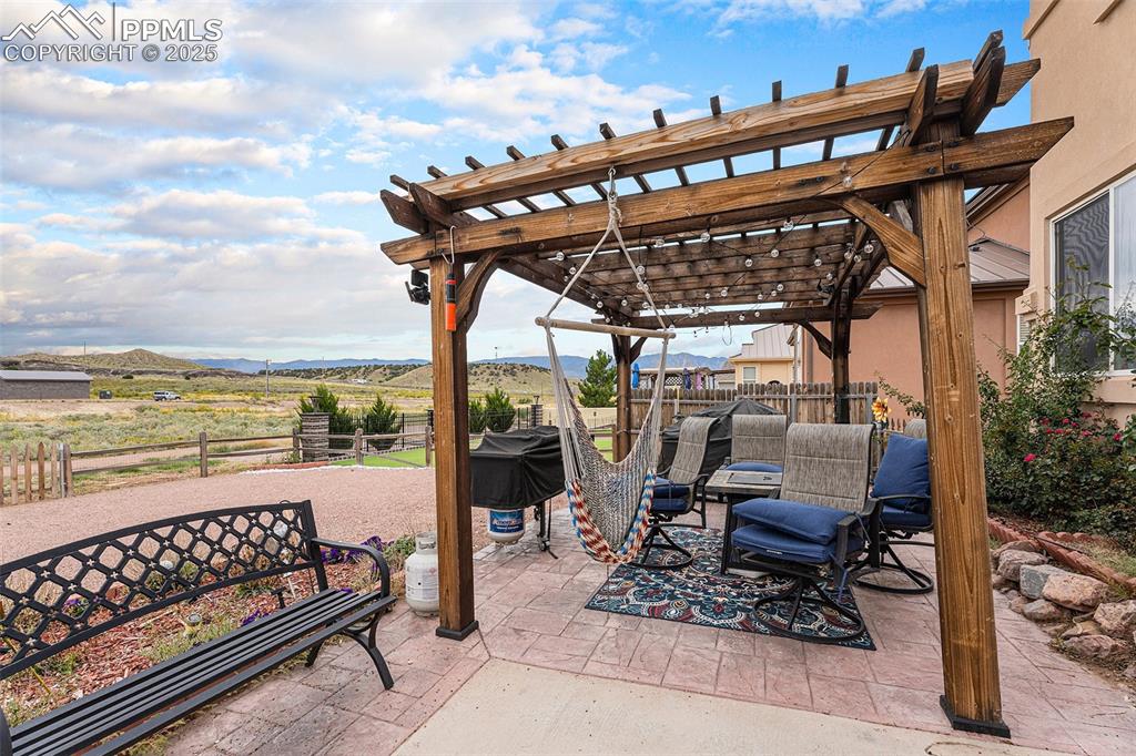Image 29 of 30: Fenced backyard with a pergola, a mountain view, a patio, and a view of cou