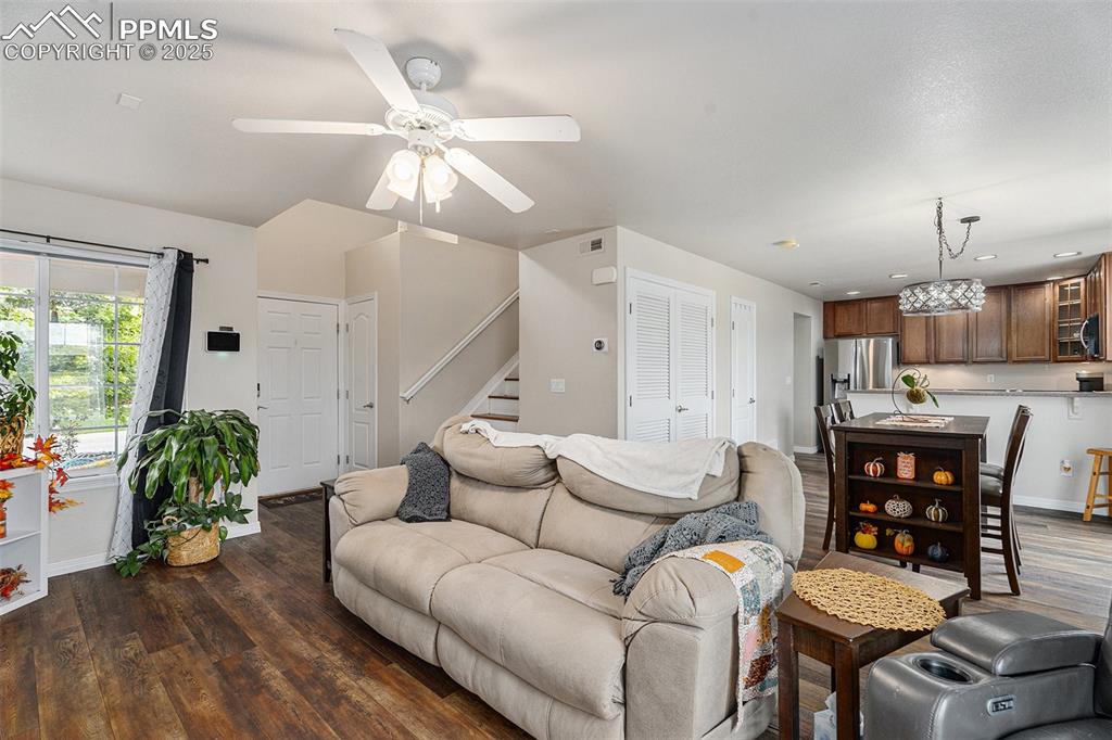 Image 8 of 30: Living room featuring dark wood finished floors, stairway, and a ceiling fa