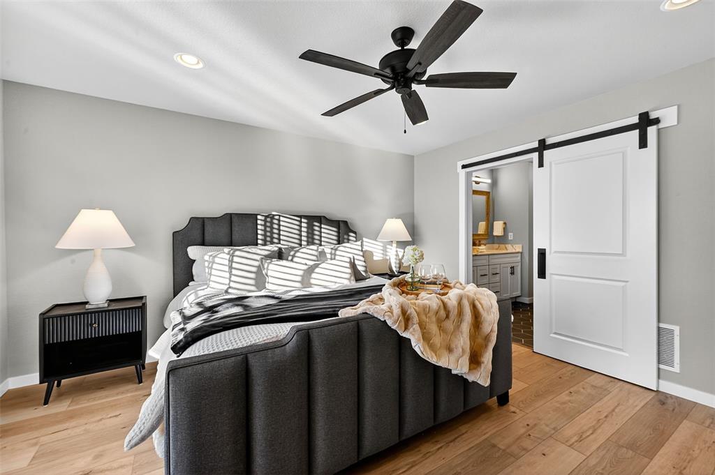 Image 15 of 32: Laminate plank flooring and barn door in Master