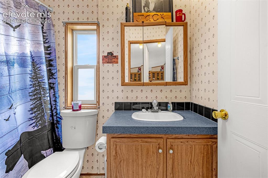 Image 20 of 38: Bathroom vanity with a built-in sink, wood-finish cabinetry, and a mirrored