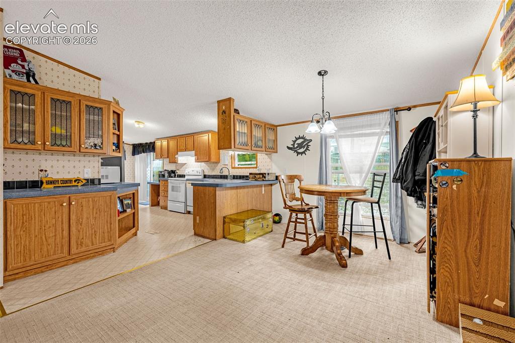 Image 9 of 38: Expansive kitchen featuring wood cabinetry, blue countertops, a double basi