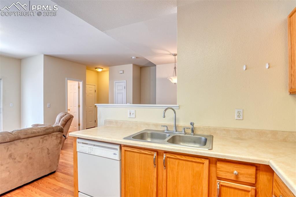 Image 15 of 32: Kitchen with white dishwasher, open floor plan, light countertops, light wo