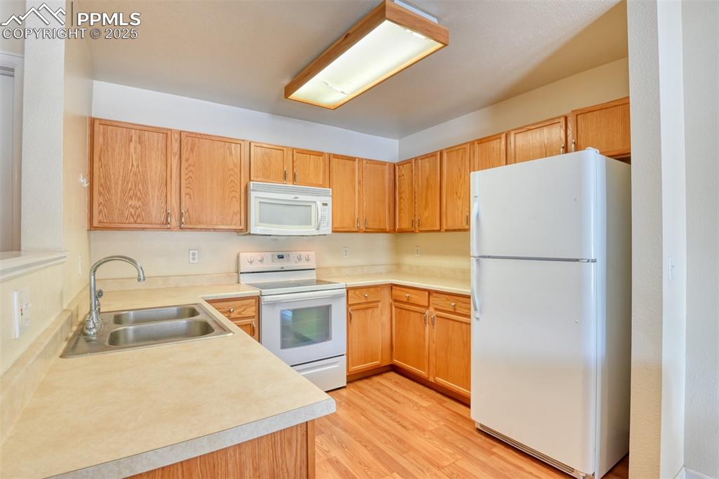 Image 16 of 32: Kitchen featuring white appliances, light wood-style flooring, and light co