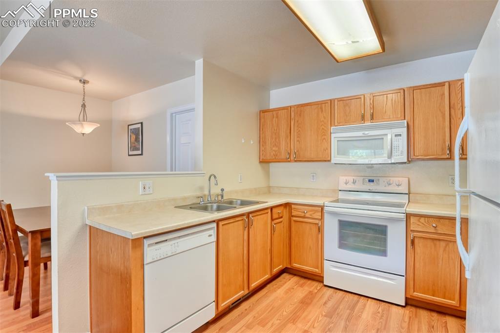 Image 17 of 32: Kitchen featuring white appliances, light wood-style floors, a peninsula, l