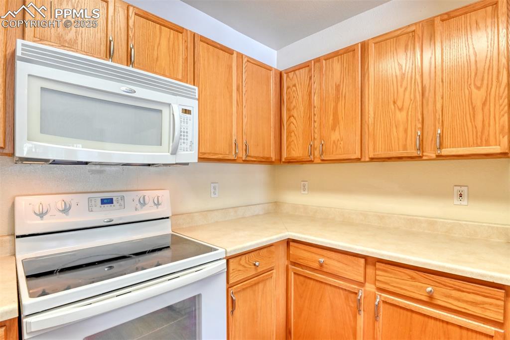 Image 18 of 32: Kitchen featuring white appliances and light countertops