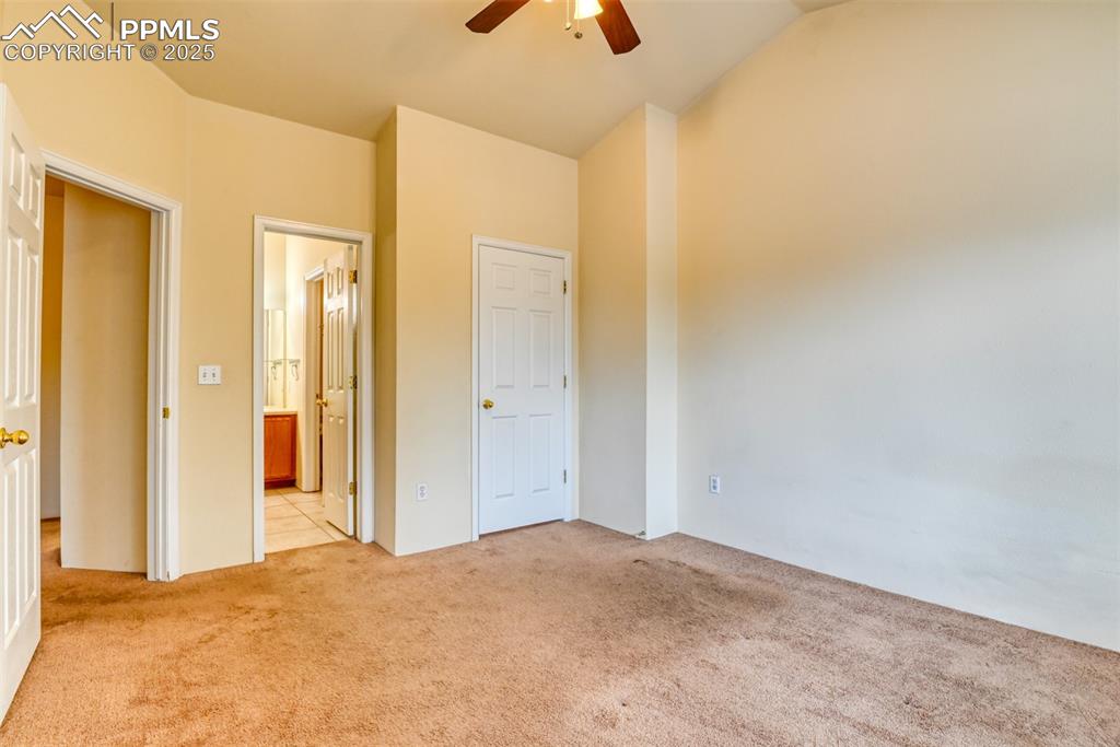 Image 29 of 32: Unfurnished bedroom featuring light carpet, ensuite bath, vaulted ceiling,