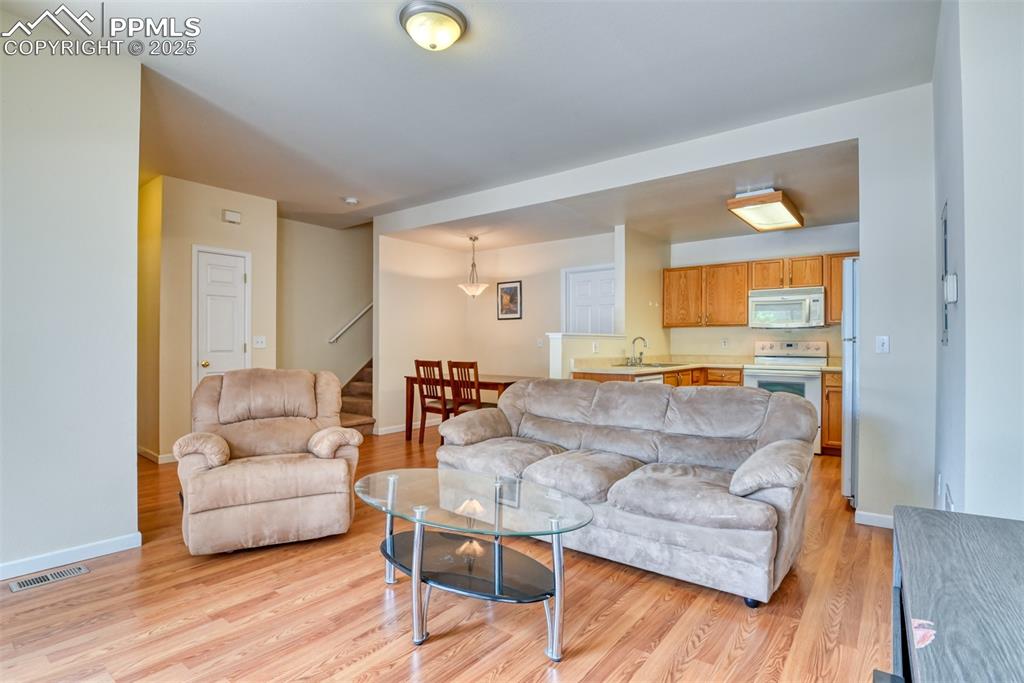 Image 9 of 32: Living room with stairway and light wood-style floors