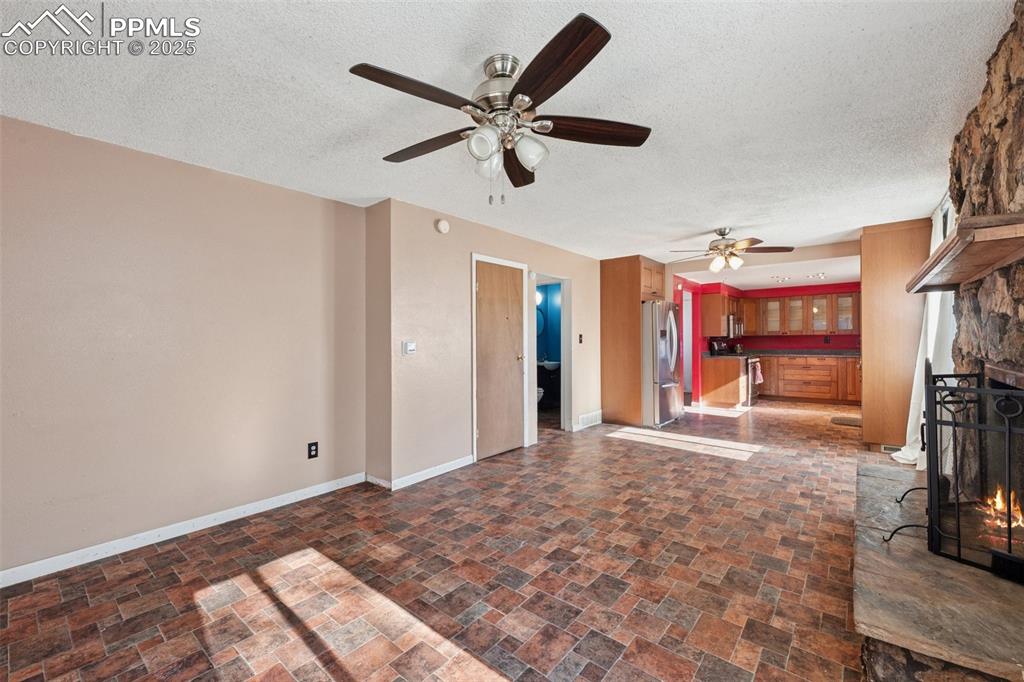 Image 13 of 41: Unfurnished living room featuring a fireplace, a textured ceiling, and dark