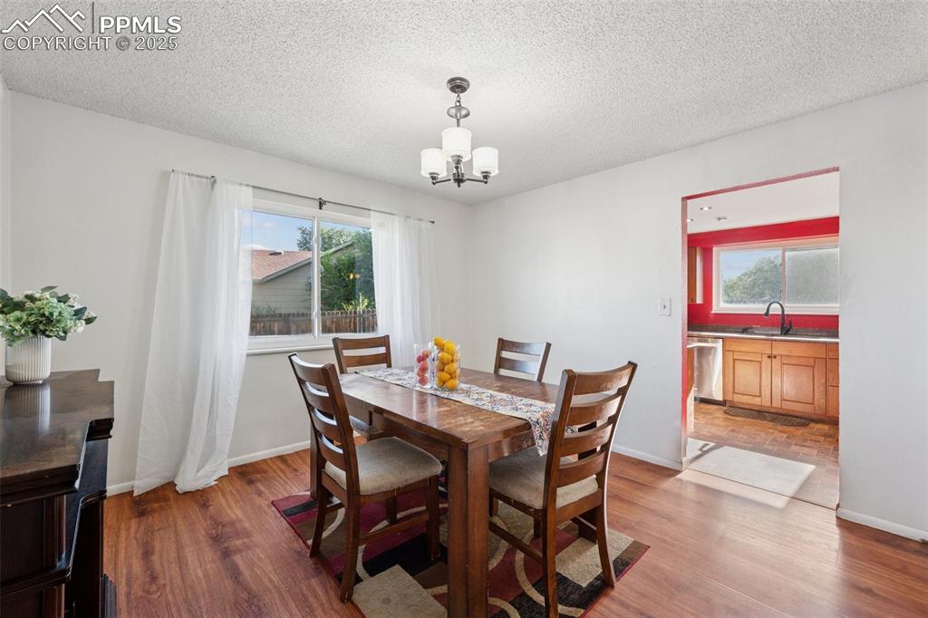 Image 18 of 41: Dining space featuring wood finished floors, a textured ceiling, and a chan