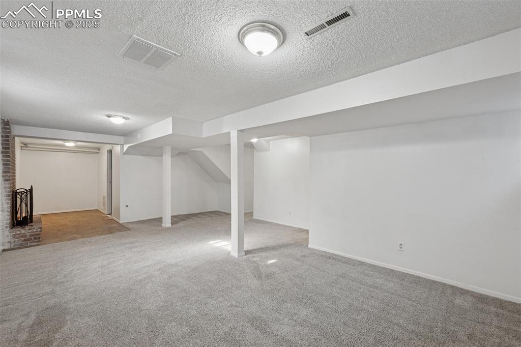 Image 29 of 41: Finished basement with carpet flooring and a textured ceiling
