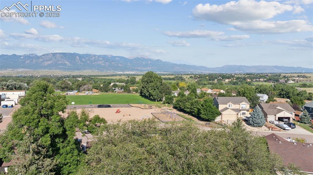 Image 3 of 41: Aerial perspective of suburban area featuring mountains and a tree filled l