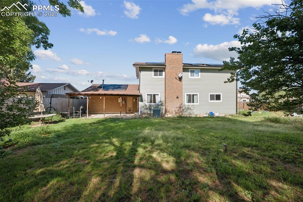Image 39 of 41: Back of house with solar panels, a patio area, and a chimney