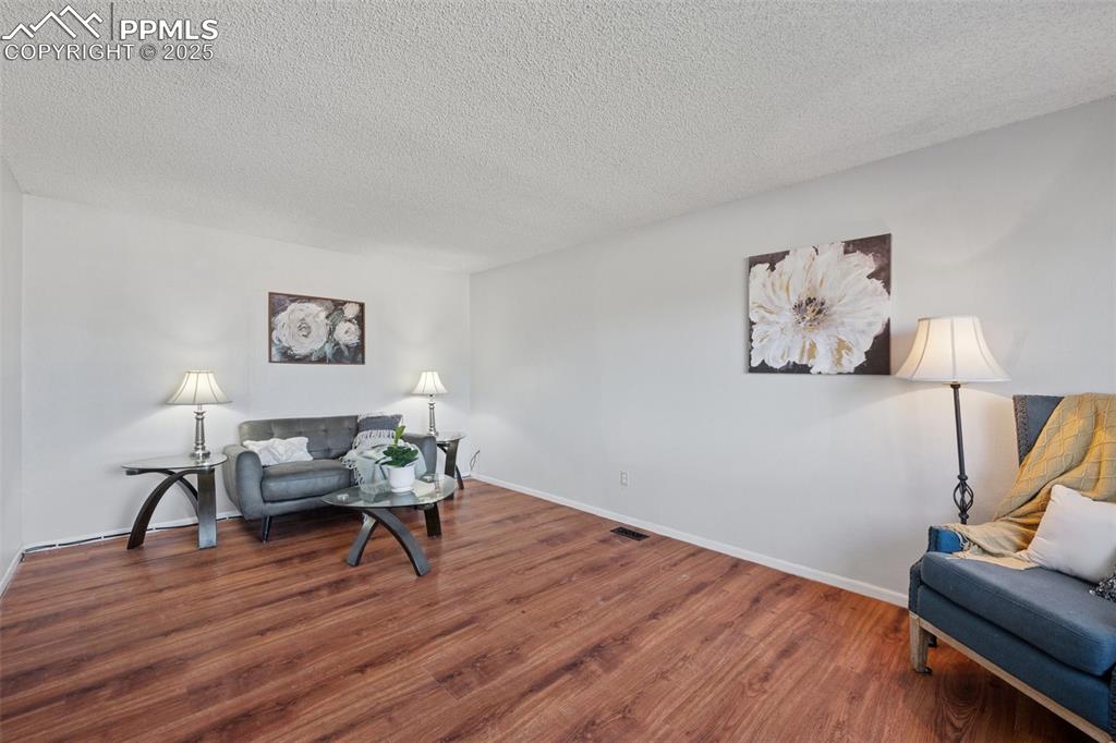 Image 7 of 41: Living area featuring wood finished floors and a textured ceiling