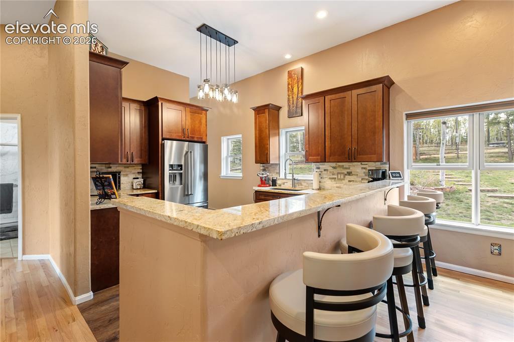 Image 10 of 40: Kitchen featuring a breakfast bar with granite countertops and seating, dar