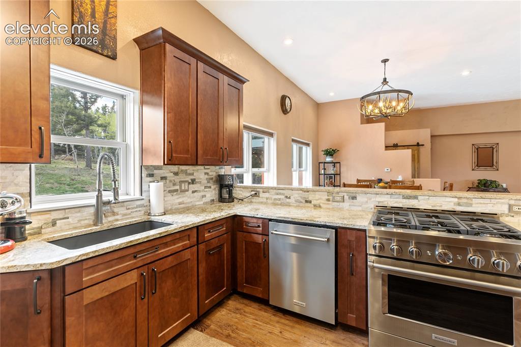 Image 14 of 40: Modern kitchen featuring rich wood cabinetry, granite countertops, a stainl
